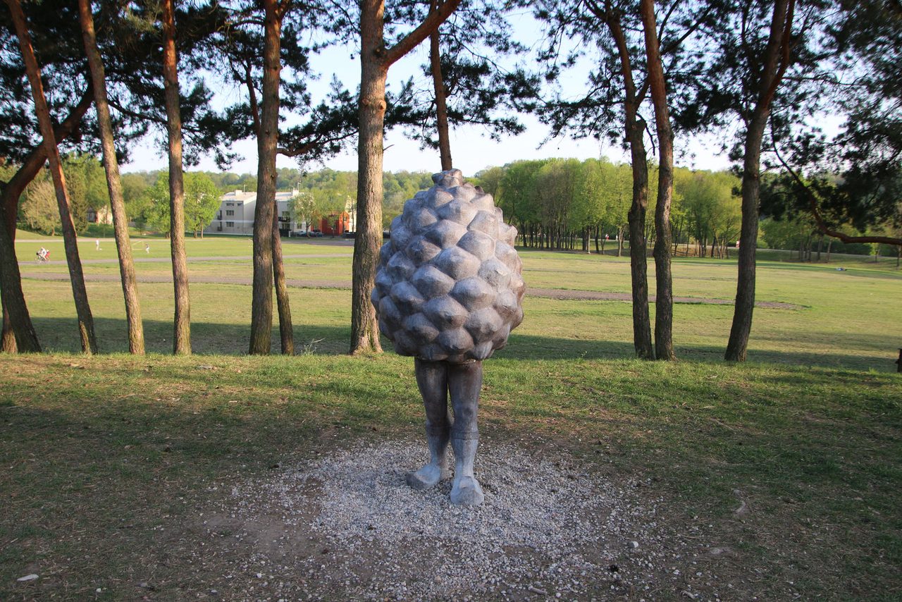 The whimsical "Pine Cone Man" sculpture in a green park